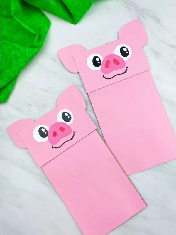 two pig paper bag puppet crafts on marble background 