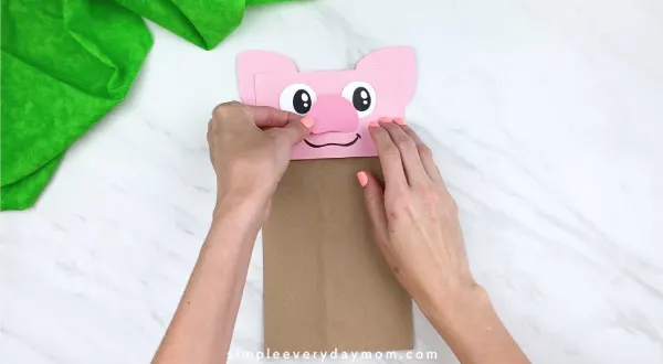 hands gluing on nose on paper bag pig craft