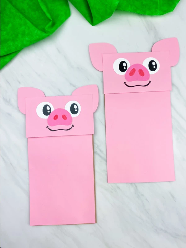 two paper bag pig crafts on marble background 