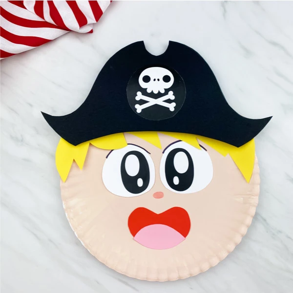 paper plate pirate craft on marble background with red and white striped fabric 