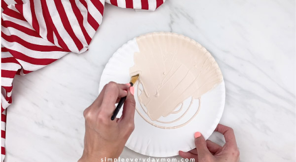 hands painting paper plate peach