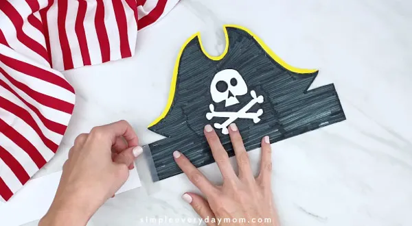 hand taping together paper pirate headband 