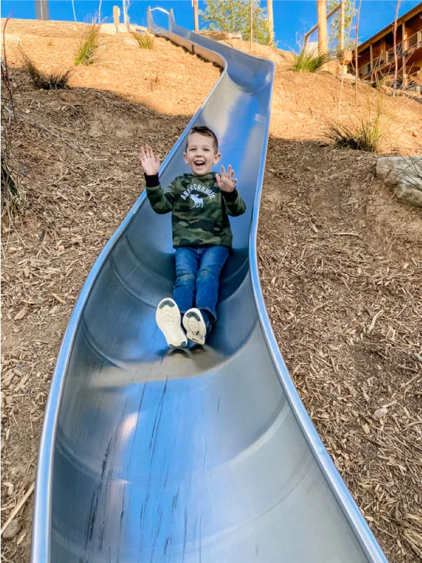 child sliding down metal slide 