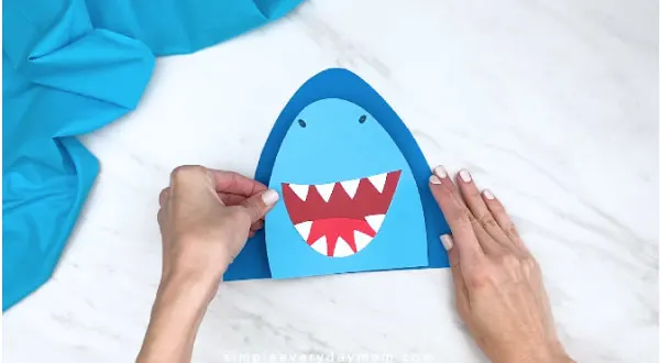 hands gluing on center of shark head to shark body 