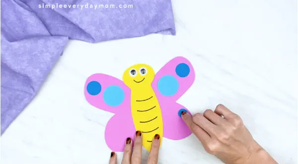 hands gluing on blue circle to butterfly card craft 