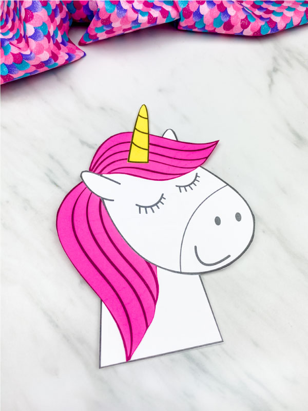 pink paper unicorn craft with marble background and colorful fabric 