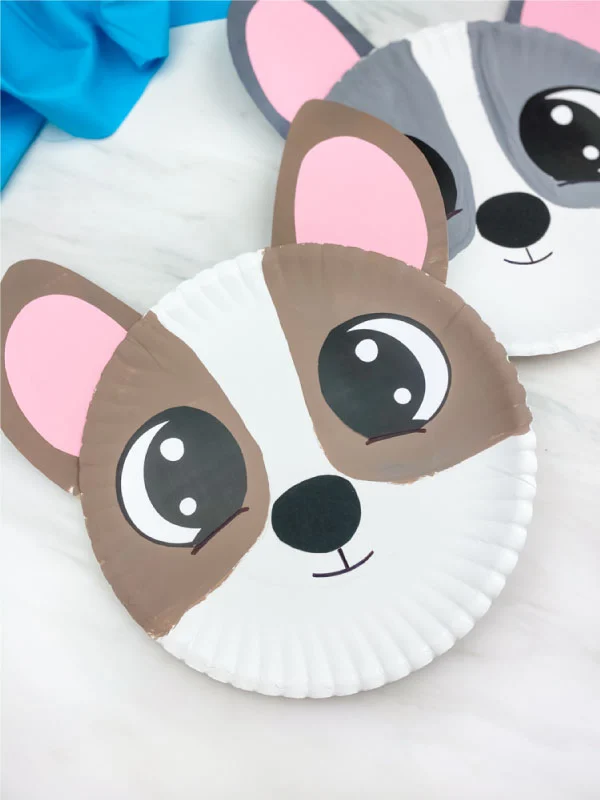 closeup of brown paper plate dog craft with gray paper plate dog craft in background 