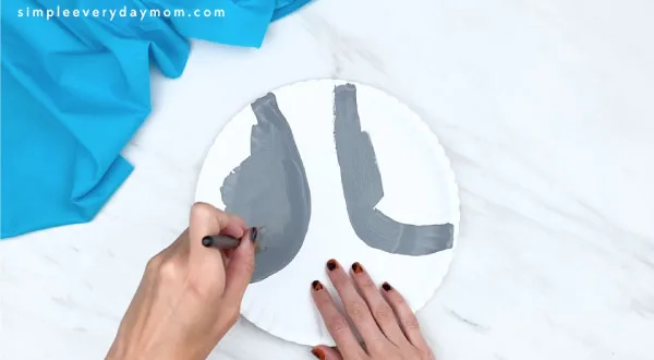 hands painting parts of paper plate gray 