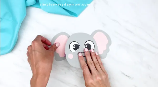 hands gluing ears onto elephant paper craft