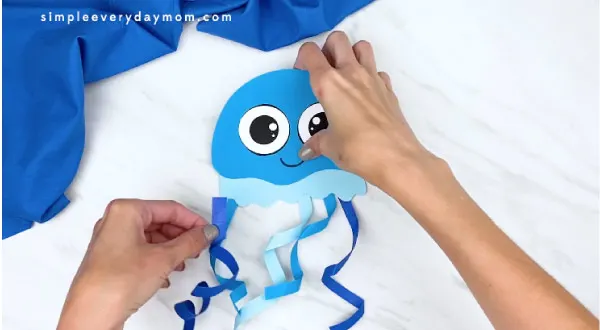 hands gluing curled ribbon onto jellyfish 