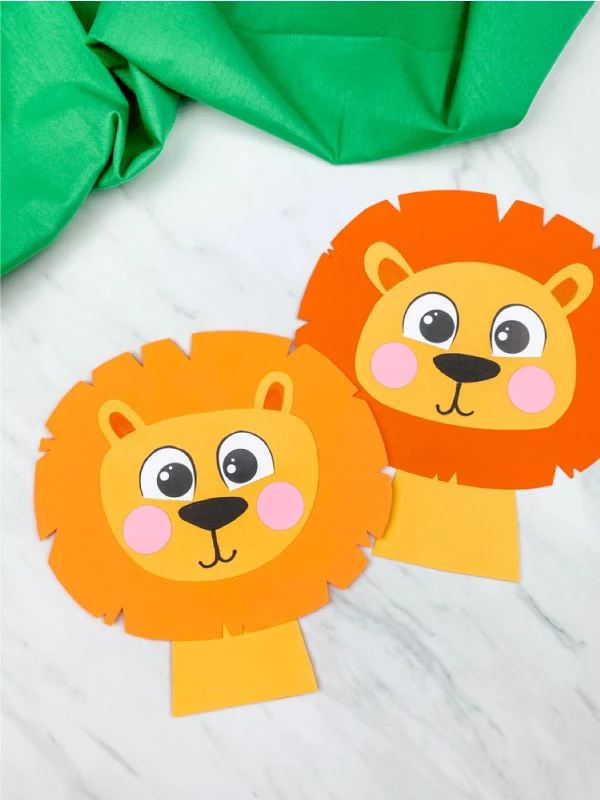 light orange maned and dark orange maned paper lions on marble background with green fabric 