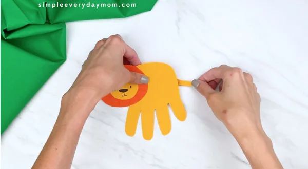 hands gluing on tail to handprint lion 