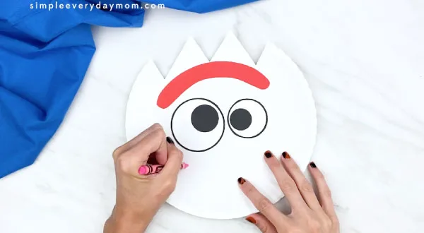 hands coloring in Forky's cheeks on paper plate 
