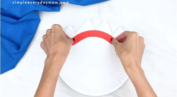hands gluing on forky's eyebrows to paper plate 
