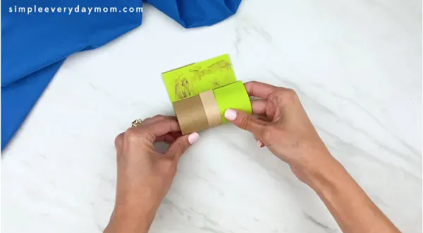 hands gluing Yoda template to cardboard tube 