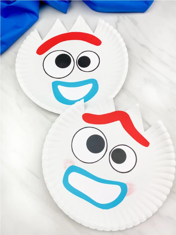 two paper plate forky crafts on marble background with blue fabric 