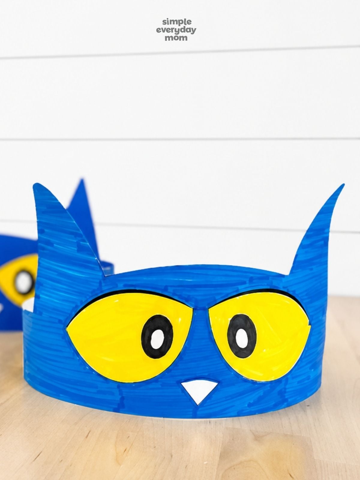 Close-up of a hand-colored blue Pete the Cat headband with yellow eyes and a white triangular nose.