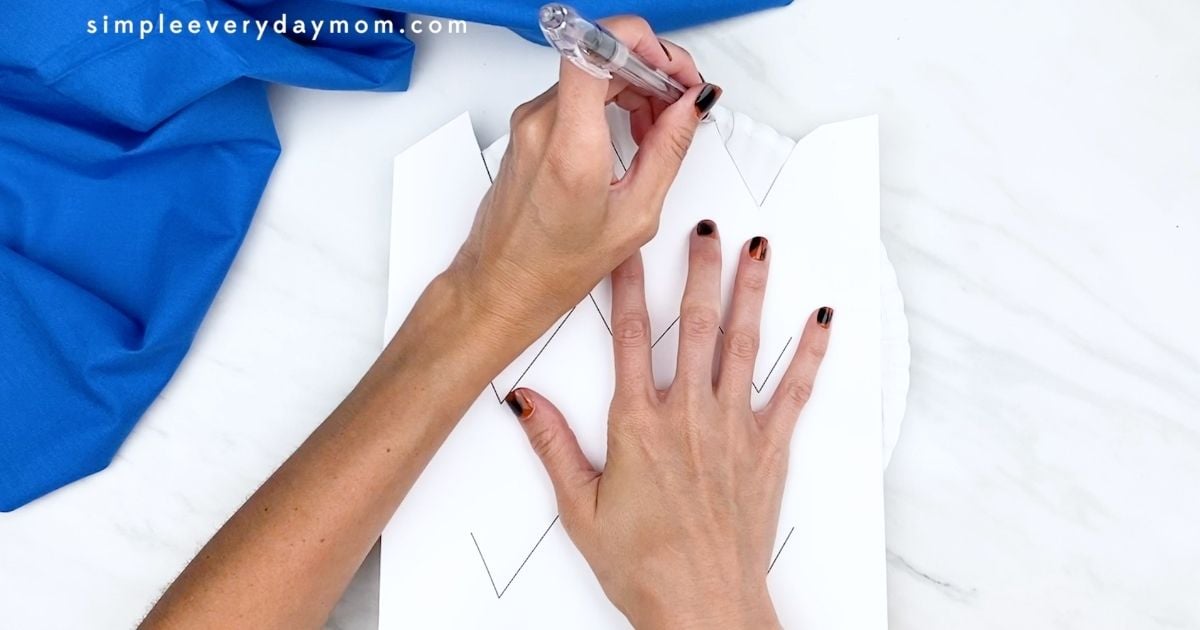 Hand tracing a printable template onto a paper plate for a Forky craft.