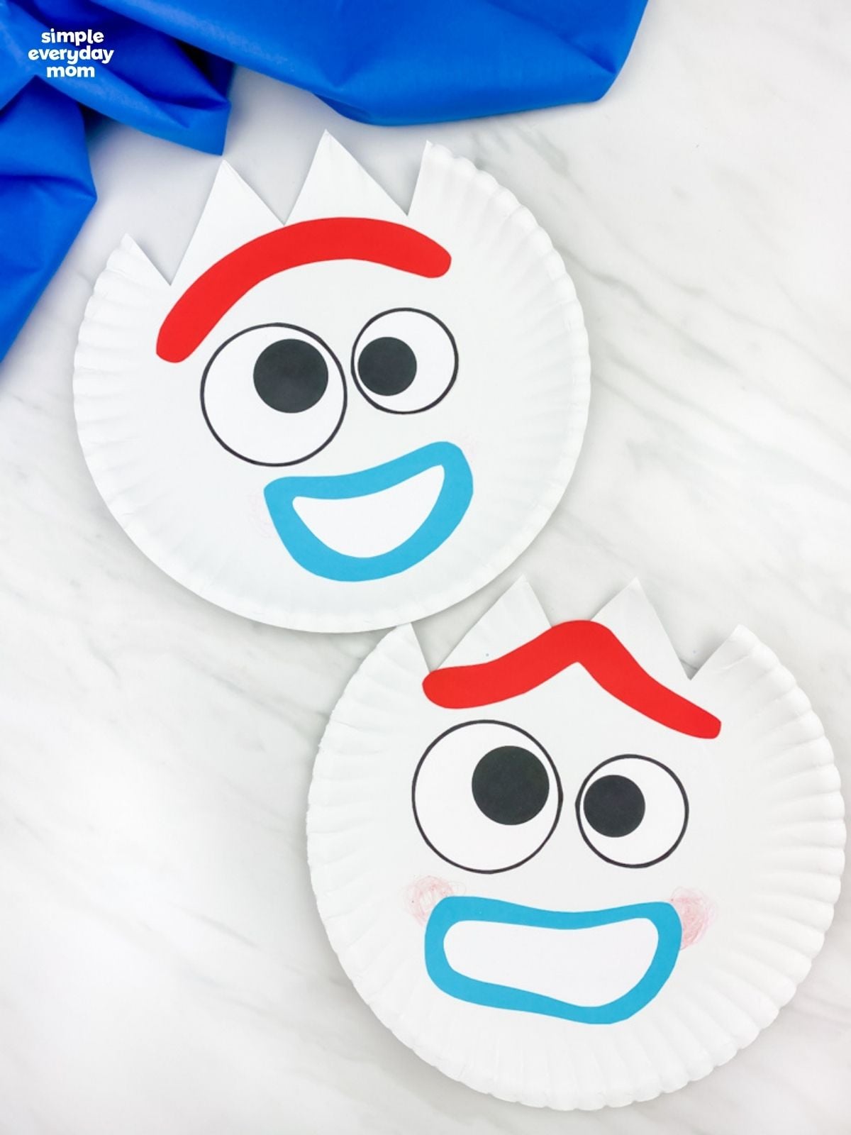 Two finished Forky paper plate crafts with different facial expressions displayed on a tabletop.
