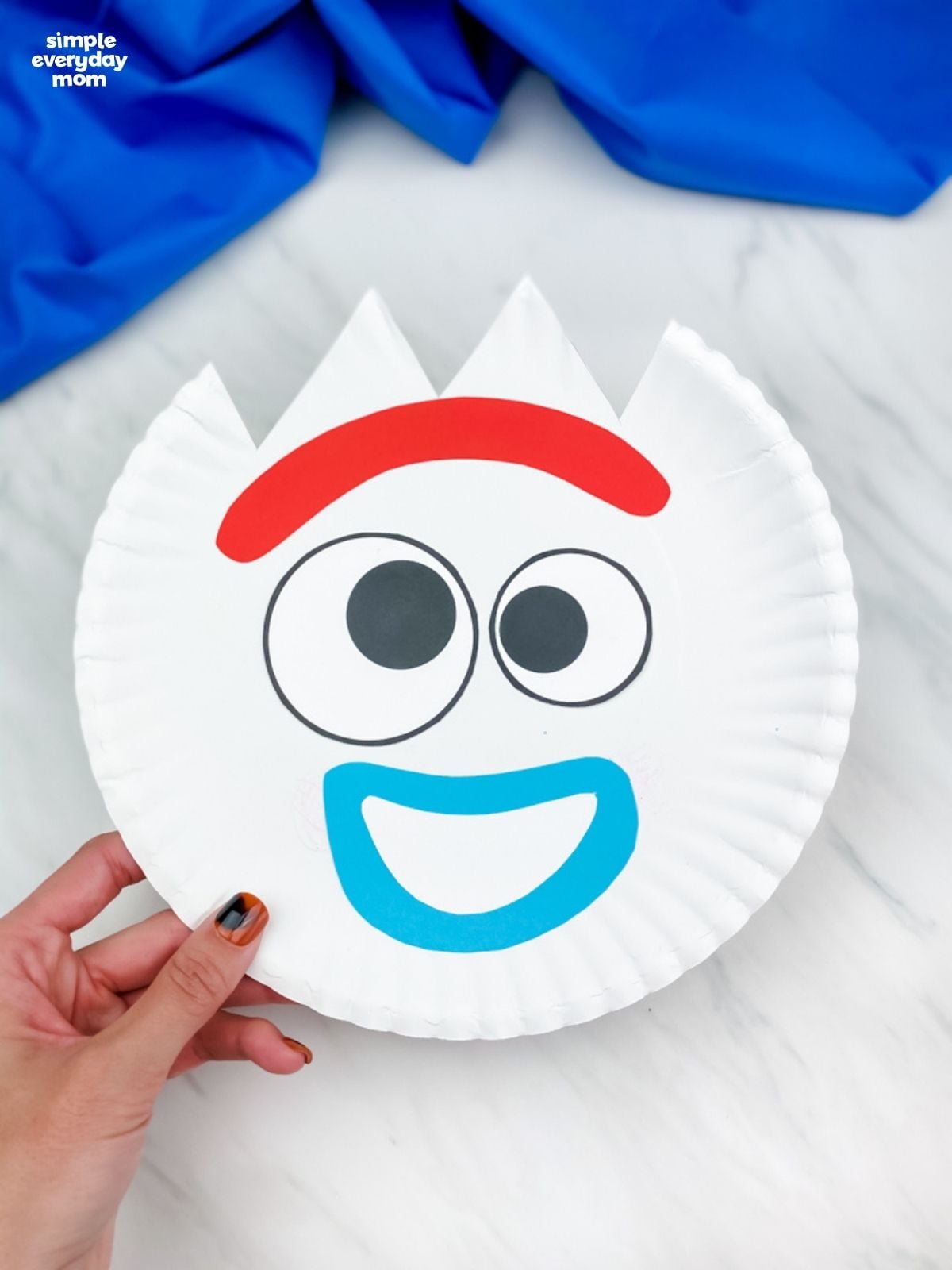 Hand holding a finished surprised Forky paper plate craft.