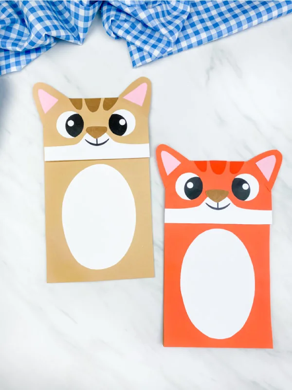 brown and orange paper bag cat puppet on marble background with blue checkered fabric