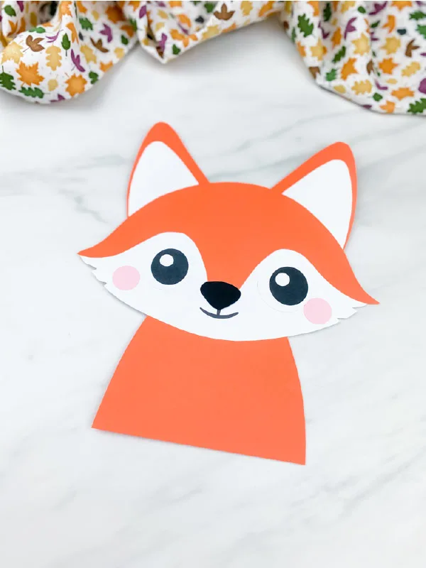 closeup image of one paper fox crafts  on marble background with leaf print fabric