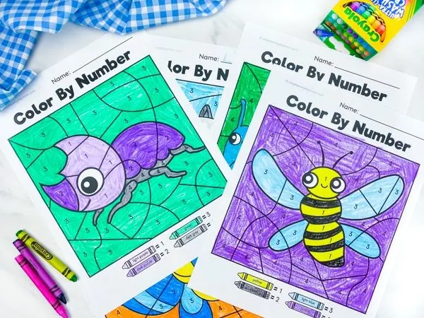 stack of bug color by number worksheets on marble background with crayons 