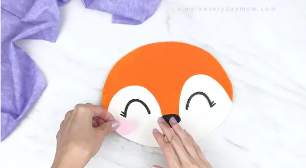 hands gluing on pink cheeks onto paper plate fox 