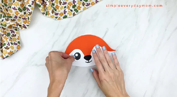 hands gluing on eyes to paper fox face 
