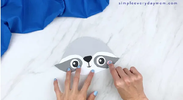 hands gluing on pink cheek to paper raccoon craft 