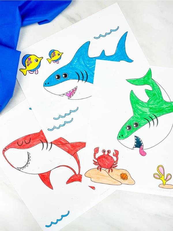 red, blue and green shark coloring pages for kids on marble background with blue fabric