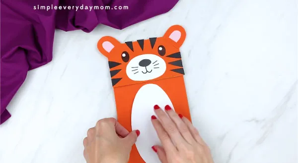 hands gluing stomach to tiger