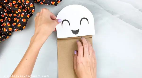 hands gluing ghost head onto paper bag