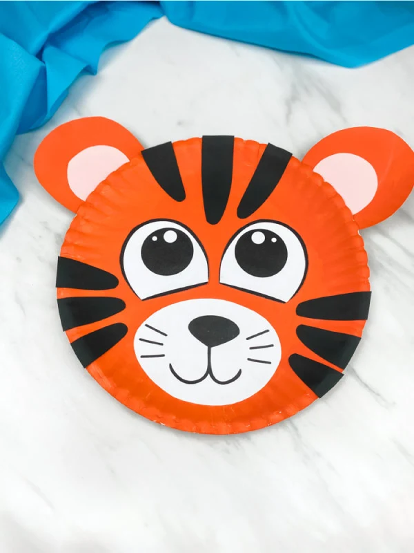 one paper plate tiger craft on marble background with blue fabric 