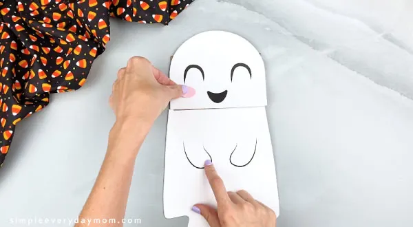 hands gluing paper bag ghost head on flap