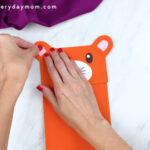 hands gluing ears to tiger