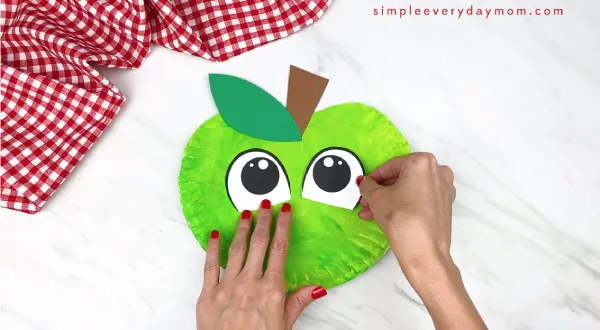 hands gluing on stem on paper eyes on paper plate apple 