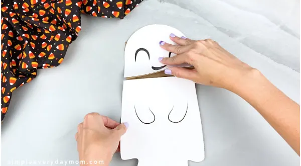 hands gluing ghost body onto paper bag
