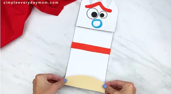 hands gluing forky clay base paper onto puppet craft