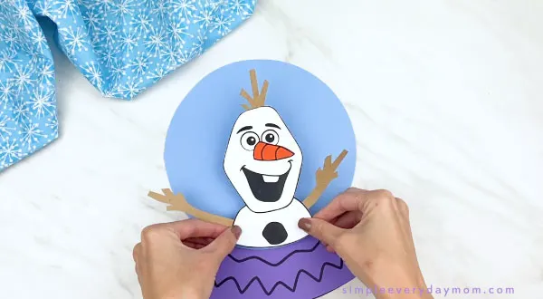 hands gluing olaf to paper snowglobe
