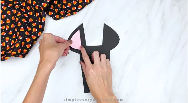 hands gluing pink inner ear to paper bat