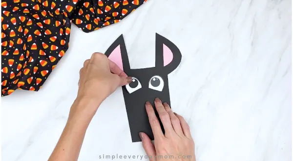 hands gluing eyes onto paper bat craft