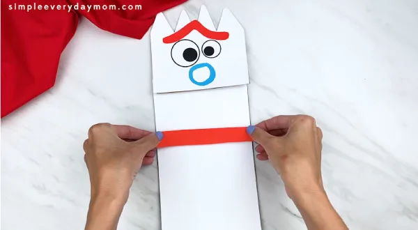 hands gluing arms onto forky paper bag puppet craft