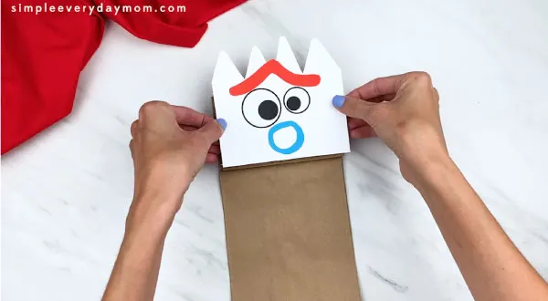 hands gluing forky face onto paper bag flap