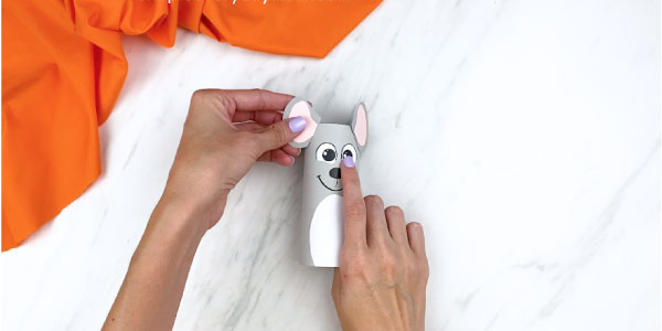 Hand gluing ears onto toilet paper roll mouse