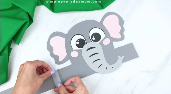 Hands taping headband extenders to elephant headband craft