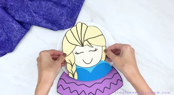hands gluing paper Elsa to snowglobe ball
