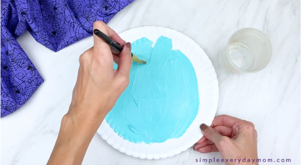hands painting paper plate blue