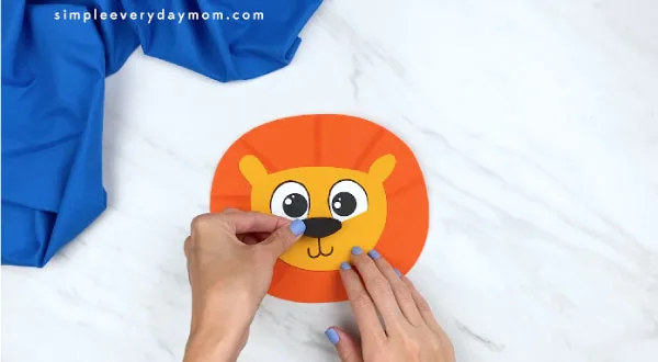 hands gluing nose onto paper lion face