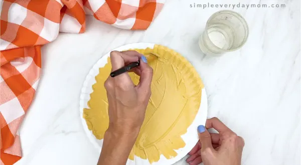 hand painting paper plate a muted yellow brown color